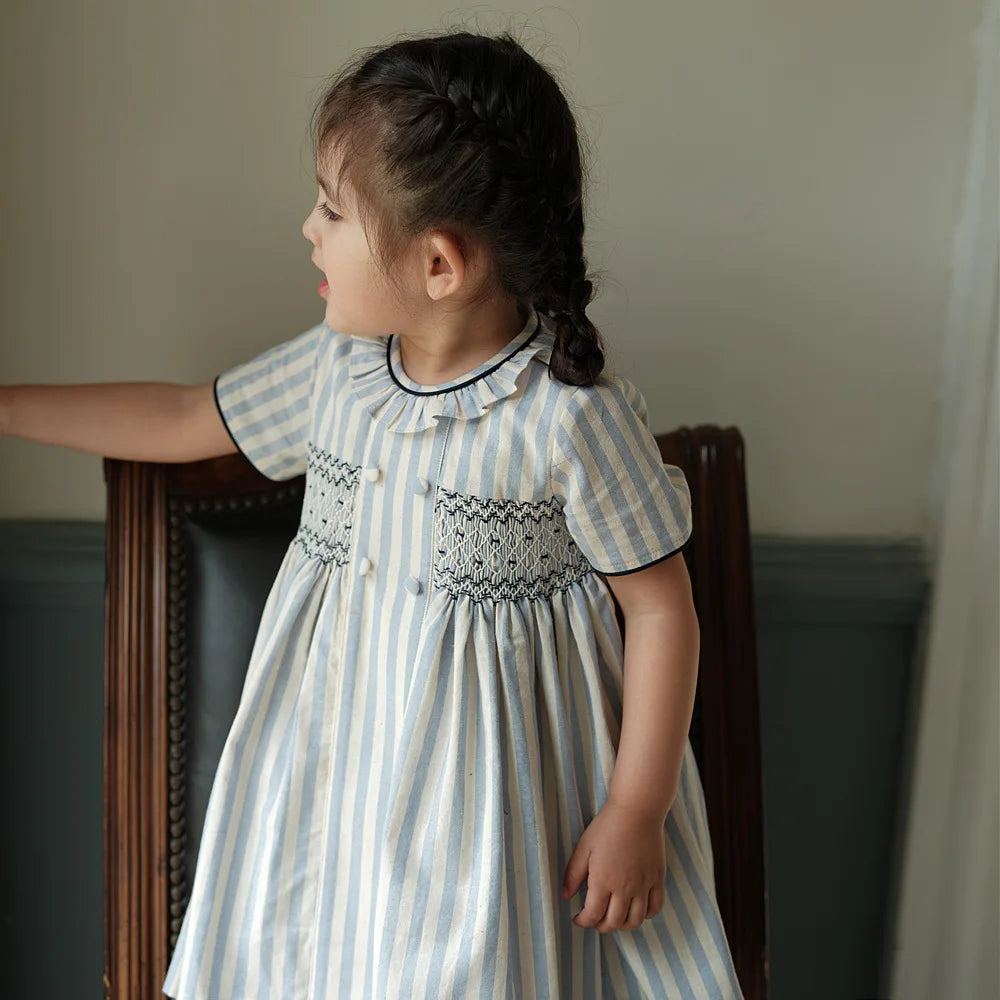 Vestido para niña, estilo moda española de alta gama, bordado punto smock y botones sobre rayas, ribete azul marino, traje de algodón de manga corta, para vacaciones de primavera y verano