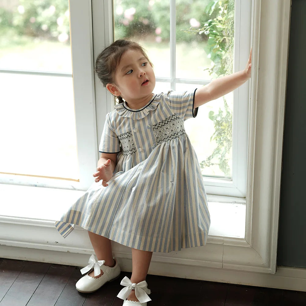 Vestido para niña, estilo moda española de alta gama, bordado punto smock y botones sobre rayas, ribete azul marino, traje de algodón de manga corta, para vacaciones de primavera y verano